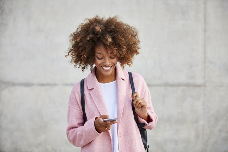Young woman in a pink coat using a smartphone