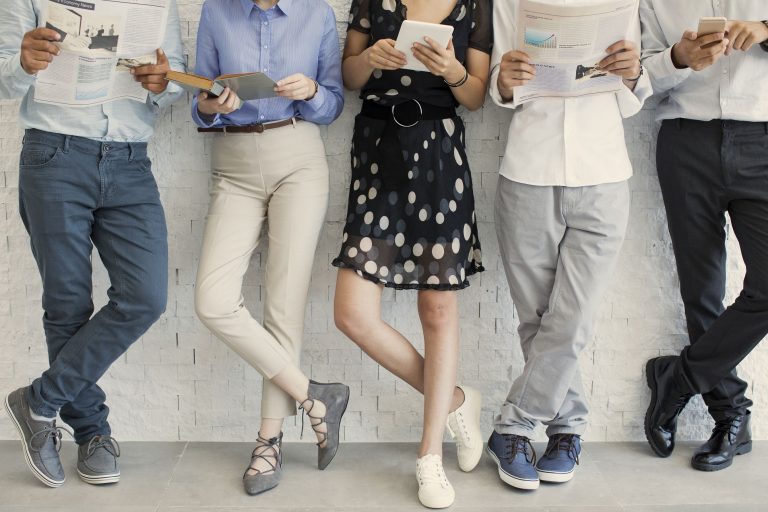 Line-up of people reading while standing against a wall