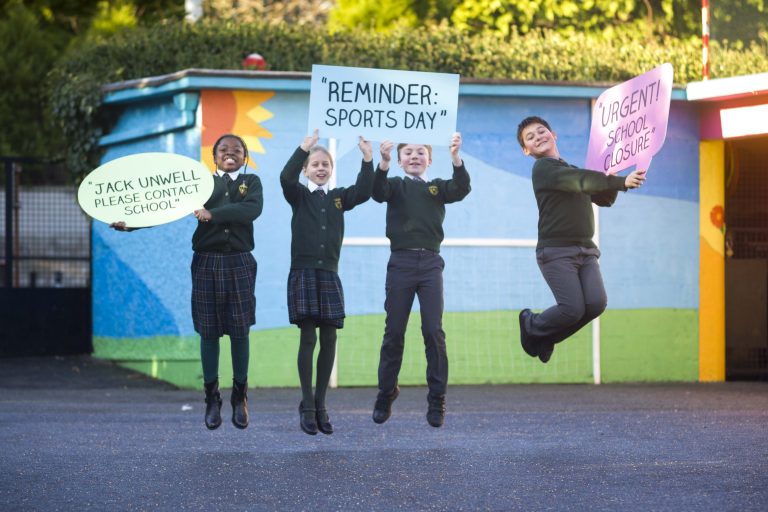 Group of school children jumping and holding up signs in the school yard