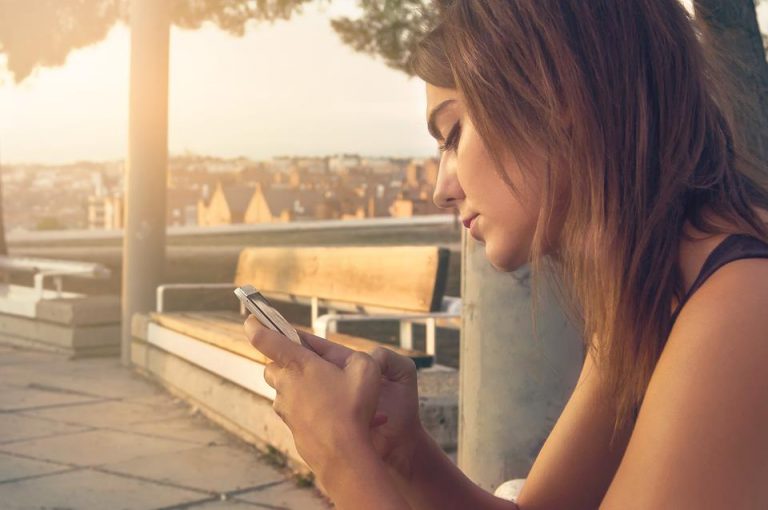 Young woman using a mobile phone on a park bench